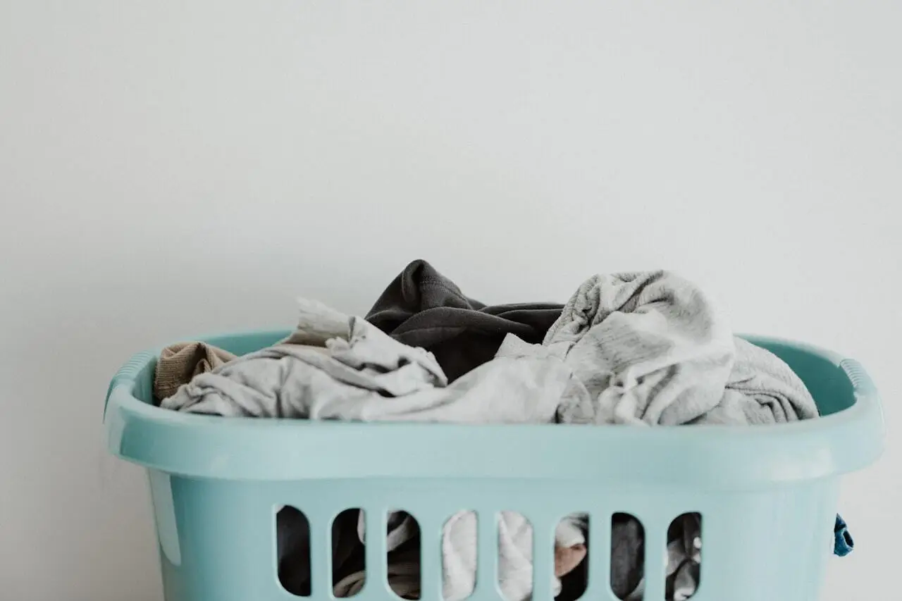 Blue laundry basket overflowing with assorted clothes ready for the laundromat
