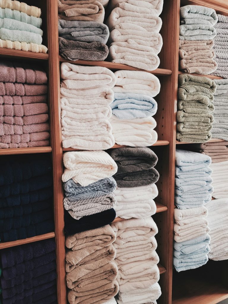 Neatly folded towels organized on wooden shelves from a wash and fold laundry service